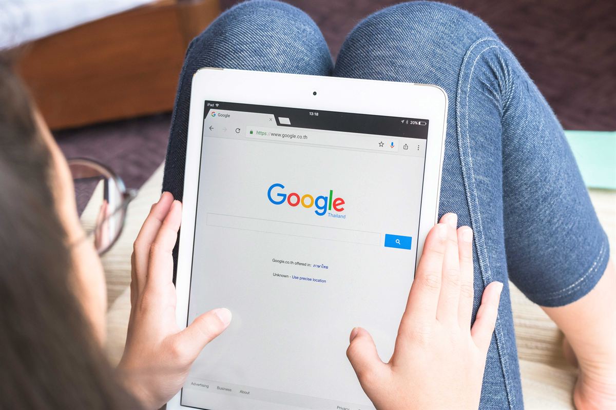 Hände halten ein Tablet mit geöffneter Google-Suche